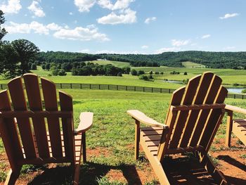 Chairs and tables on field against sky