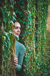 Young woman standing against trees