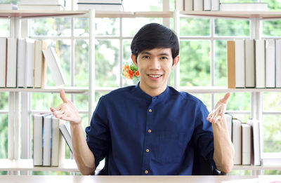 Portrait of young man standing against window