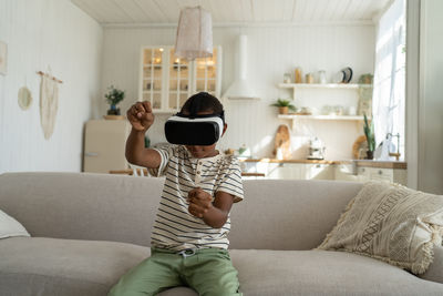 Young woman using mobile phone while sitting on sofa at home