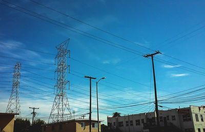 Low angle view of electricity pylon against blue sky