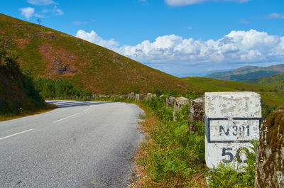 Road leading towards mountains against sky