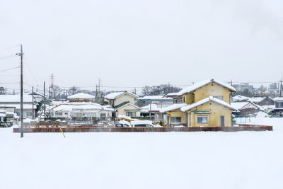 Buildings by sea against clear sky