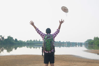 Rear view of man standing at beach against sky