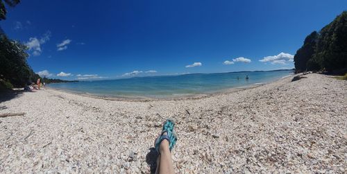 Low section of person on beach against sky