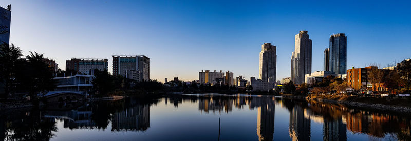 Reflection of buildings in river against clear sky