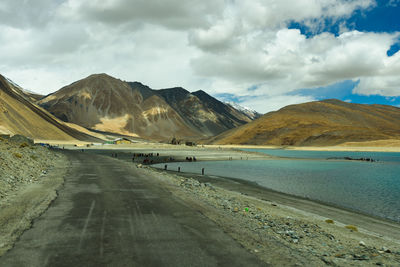 Scenic view of road by mountains against sky