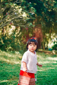 Portrait of young woman standing against trees