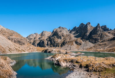 Scenic view of lake and mountains against clear blue sky