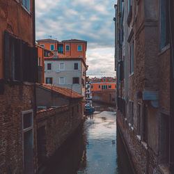 Canal amidst buildings in city against sky