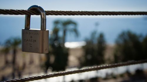 Close-up of padlock on railing against sky