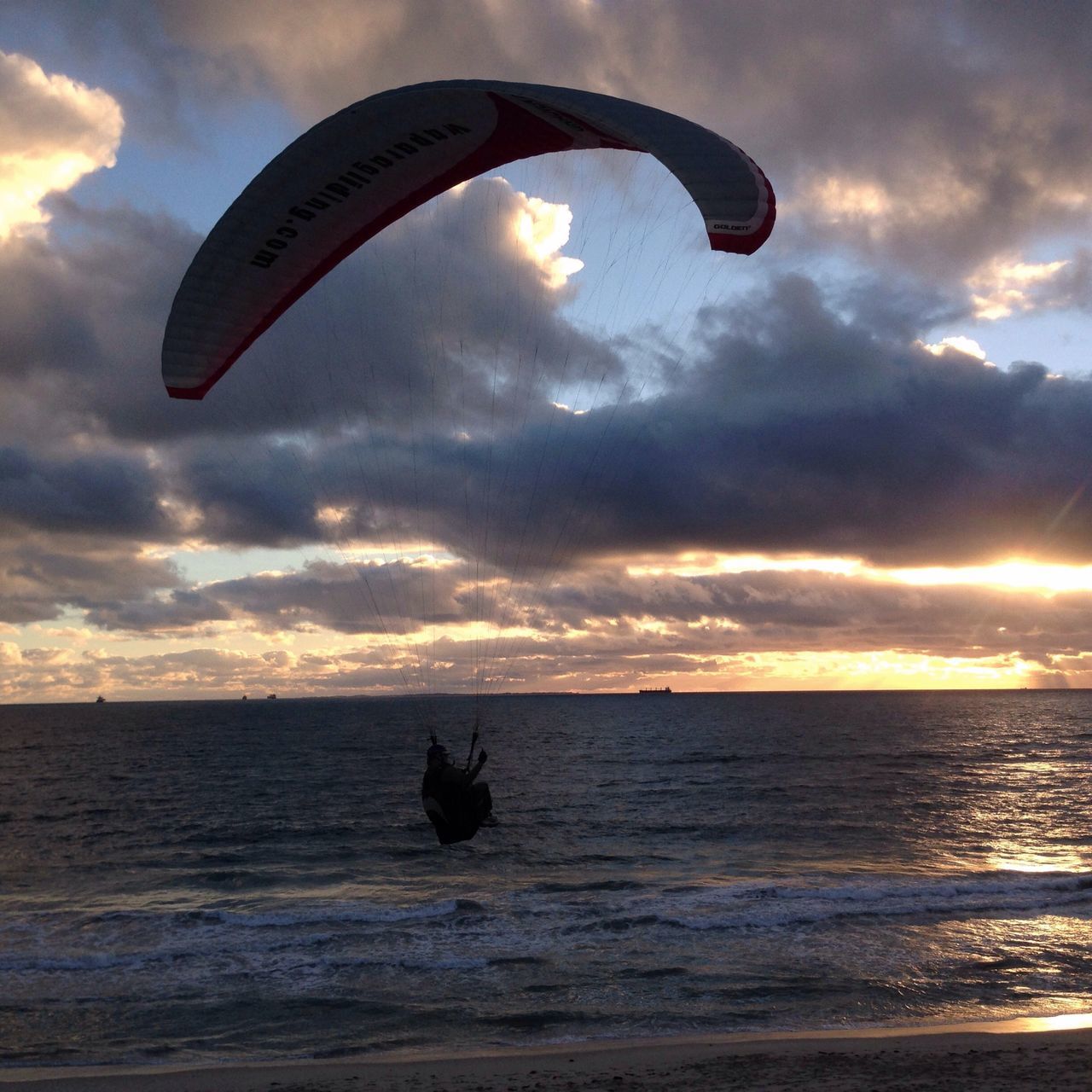 sea, sky, parachute, water, extreme sports, flying, leisure activity, mid-air, adventure, cloud - sky, transportation, beach, horizon over water, paragliding, sport, scenics, lifestyles, tranquil scene