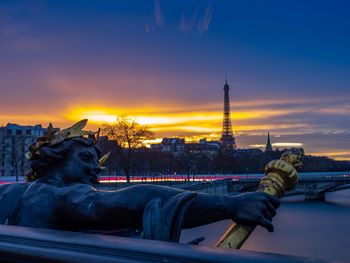 Statue in city against sky during sunset