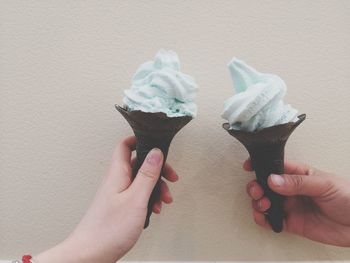 Midsection of person holding ice cream against wall
