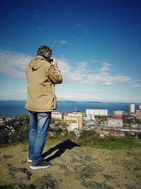 Man standing by city against sky