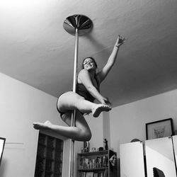 Woman performing pole dance at home