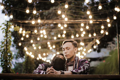 Low angle view of woman sitting on illuminated lights at night