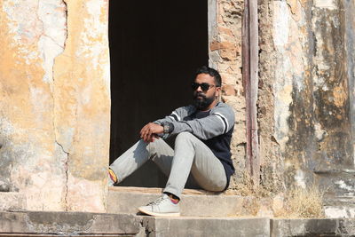 Young man sitting on wall