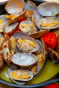 Fresh clams stewed on an iron skillet over wite rustic wood table