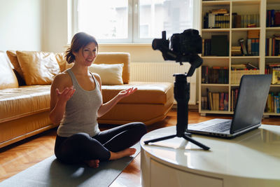 Young woman using phone while sitting on sofa