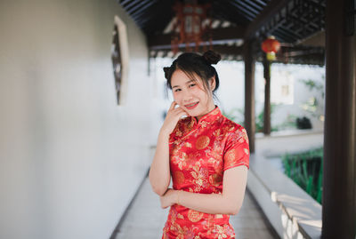 Portrait of smiling woman in traditional clothing standing in corridor