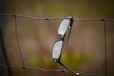 Close-up of eyeglasses on fence