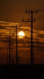 Silhouette electricity pylon against romantic sky at sunset