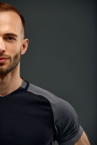 Portrait of young man standing against black background