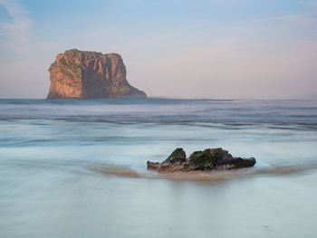 Rock formation on sea shore against sky