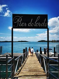 People on pier by sea against sky