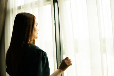 Rear view of woman looking through window