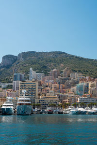 Cityscape by sea against clear blue sky