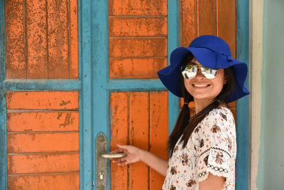 Portrait of smiling young woman standing by door