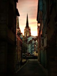 Alley amidst buildings in city at sunset