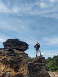 Man standing on rock against sky