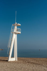 Lifeguard hut on beach against clear blue sky