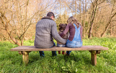 Rear view of couple sitting on bench in park