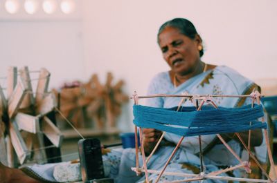 Senior woman weaving loon in workshop