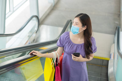 Full length of woman standing on escalator