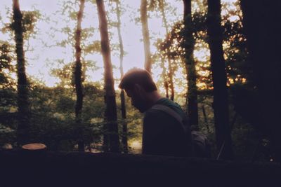 Side view of man looking at forest