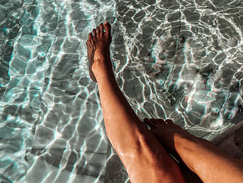 Low section of person relaxing in swimming pool