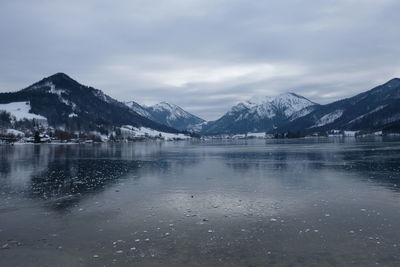 Scenic view of lake by snowcapped mountains against sky