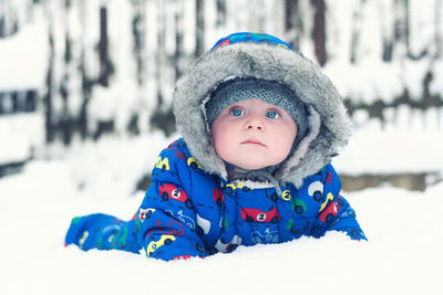 Cute baby boy lying on snow covered land