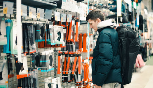 A young guy chooses a backpack in a store.