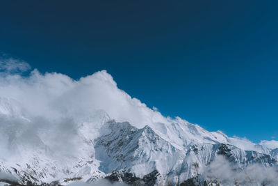 Scenic view of snowcapped mountains against blue sky