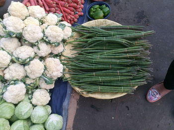 Low section of woman standing by vegetables for sale at market