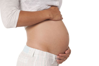 Midsection of woman touching hair against white background