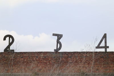 Low angle view of sign on wall against sky