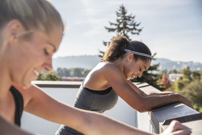 Friends exercising while leaning on railing at building terrace