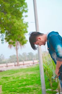 Side view of young man standing against sky